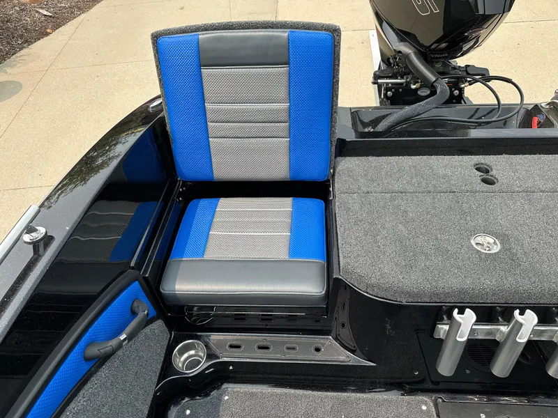 Slide: The Image of 2025 Ranger 2080MS boat interior with blue and gray seating, rod holders, and motor. - 17