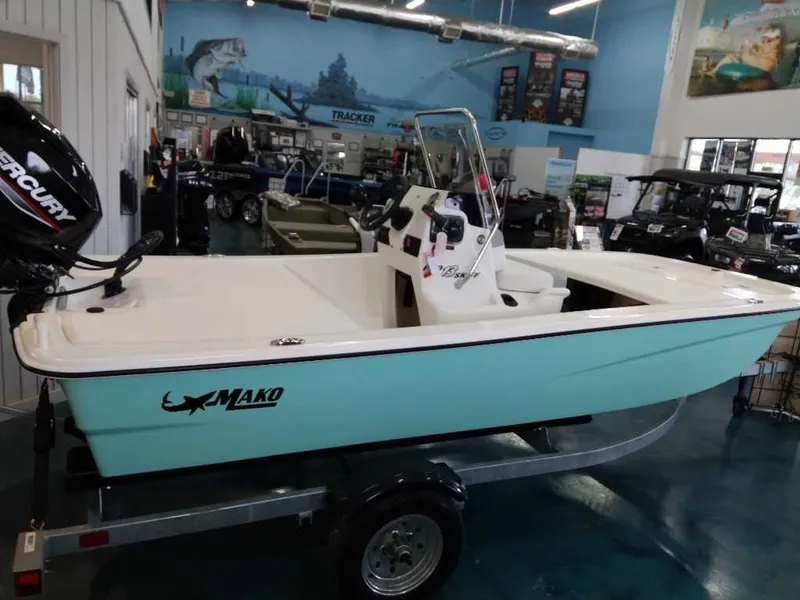 Slide: The Image of 2024 Mako Pro Skiff 13 CC boat displayed in showroom, featuring Mercury outboard motor. - 2
