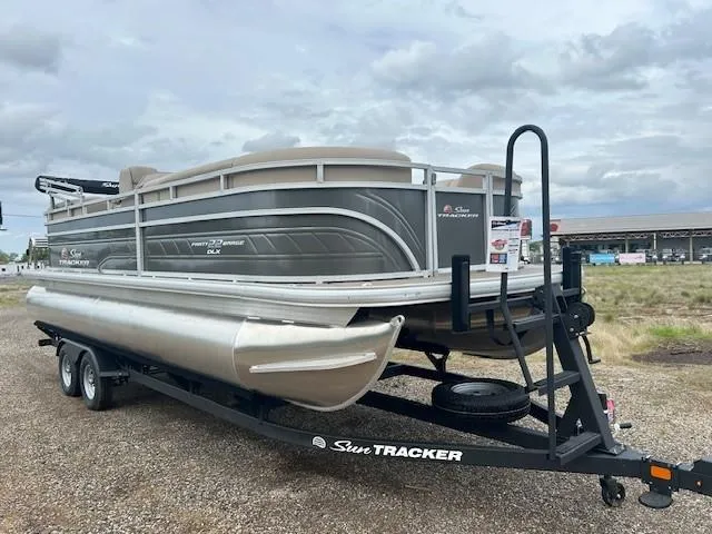 Slide: The Image of 2025 Sun Tracker Party Barge 22 DLX pontoon boat on trailer, parked outdoors. - 3