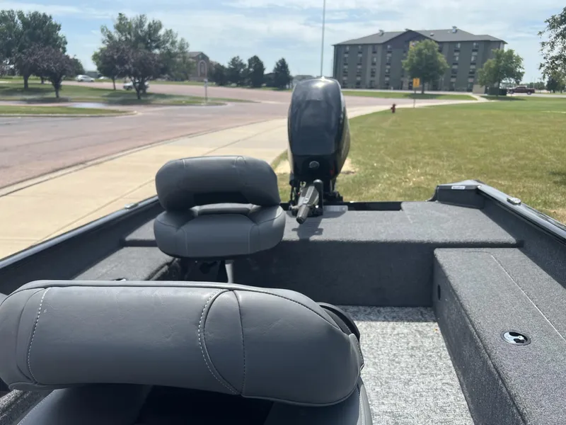 Slide: The Image of 2025 Tracker Super Guide V-16 T boat interior with gray seats and motor, parked near a road. - 5