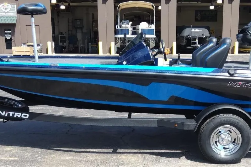 Slide: The Image of 2025 Nitro Z18 fishing boat with blue and black design, parked on a trailer. - 2