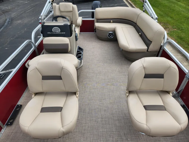 Slide: The Image of 2025 Sun Tracker Bass Buggy 16 XL Select pontoon boat interior with beige seating and steering console. - 2