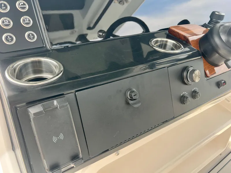 Slide: The Image of Control panel of 2025 Robalo R300 boat with cup holders and wireless charging pad. - 29