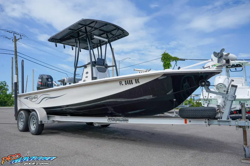 Slide: The Image of 2016 Blue Wave 2200 STL boat on trailer, parked outdoors under a clear sky. - 12
