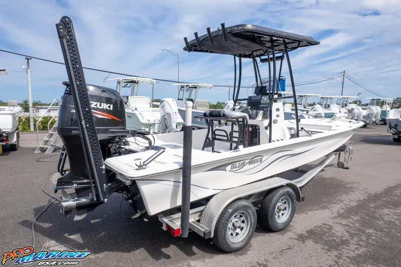 Slide: The Image of 2016 Blue Wave 2200 STL boat on trailer, featuring Suzuki outboard motor, parked outdoors. - 8