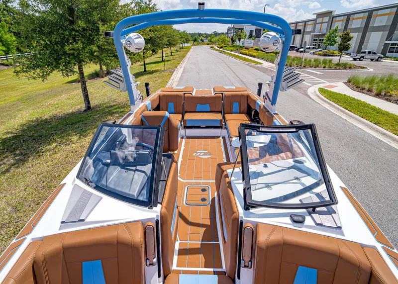 Slide: The Image of 2024 Malibu Wakesetter 24 MXZ boat with tan interior and blue accents on a sunny day. - 25
