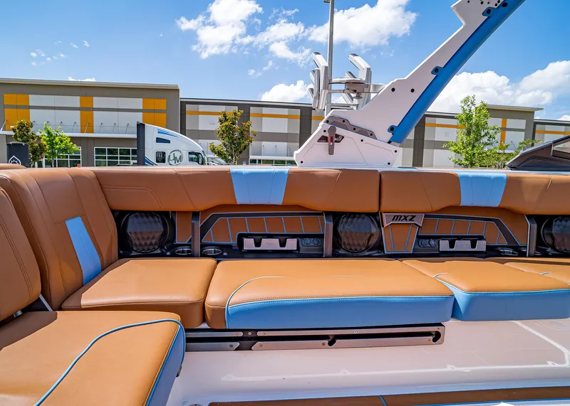 Slide: The Image of 2024 Malibu Wakesetter 24 MXZ interior with tan and blue seating, outdoor setting. - 29