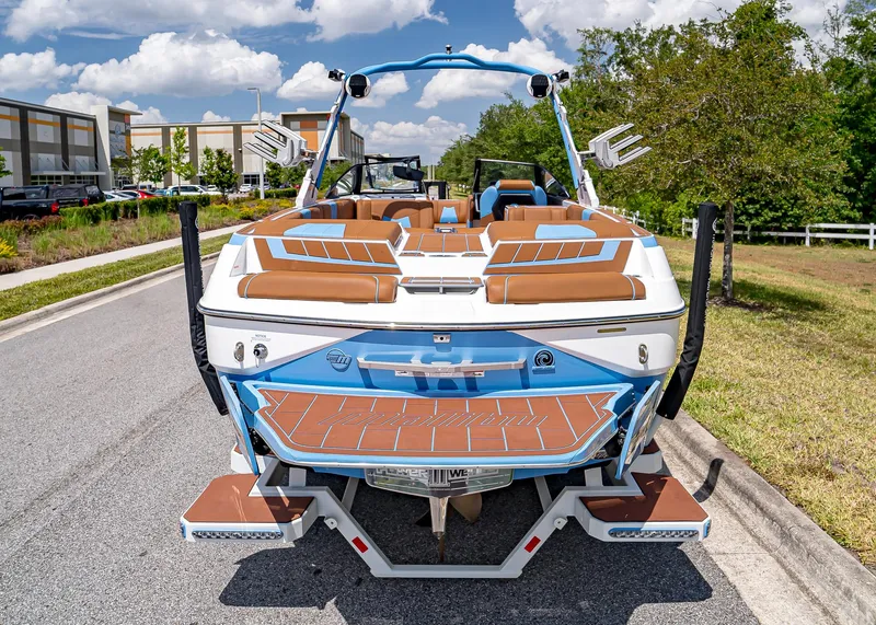 Slide: The Image of 2024 Malibu Wakesetter 24 MXZ boat, rear view, parked on a sunny street. - 7