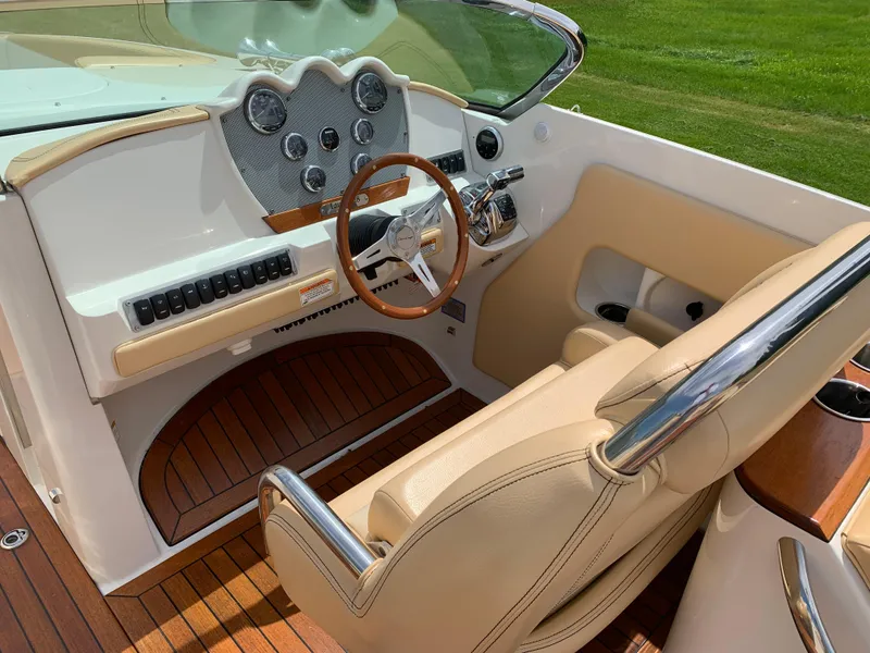 Slide: The Image of 2012 Chris-Craft Launch 28 boat interior with wooden dashboard and beige seating. - 16