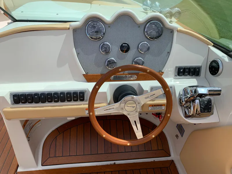 Slide: The Image of 2012 Chris-Craft Launch 28 dashboard with wooden steering wheel and classic gauges. - 17