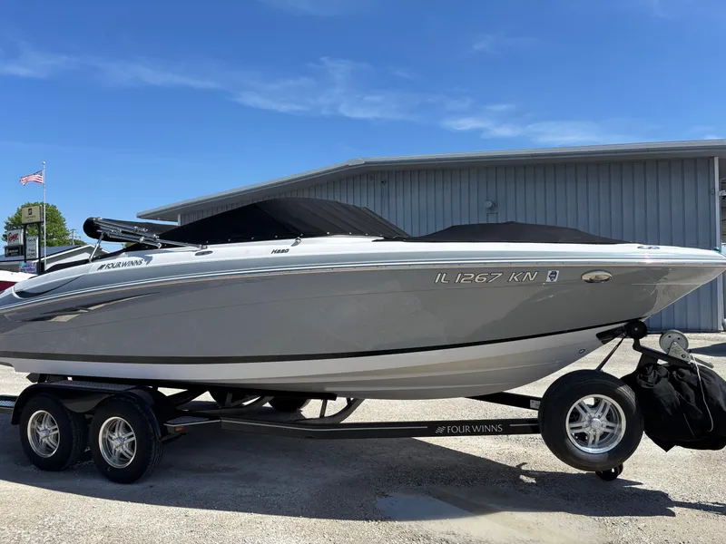 Slide: The Image of 2012 Four Winns H220 boat on trailer, parked outdoors near a building. - 2