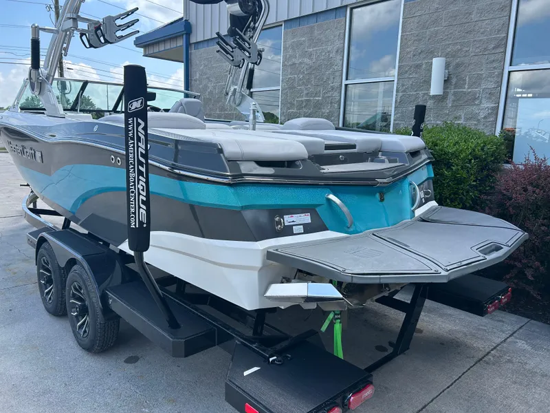 Slide: The Image of 2018 MasterCraft XT23 boat on trailer, featuring a sleek design and vibrant blue accents. - 1