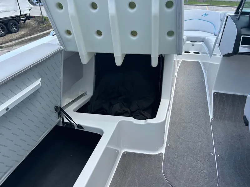Slide: The Image of 2018 MasterCraft XT23 boat interior with open storage compartment and seating area. - 10