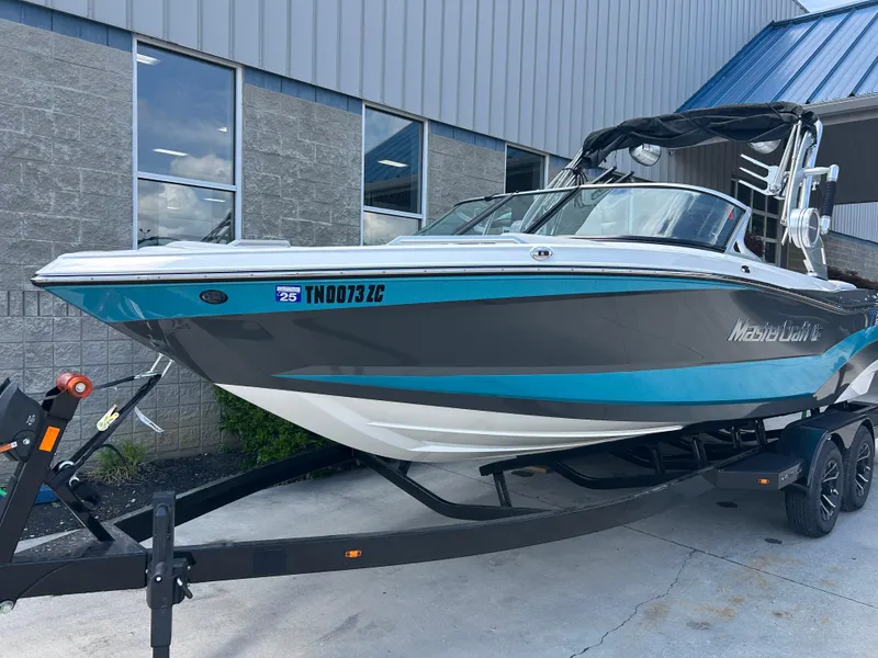 Slide: The Image of 2018 MasterCraft XT23 boat on trailer, parked outside a building. - 2