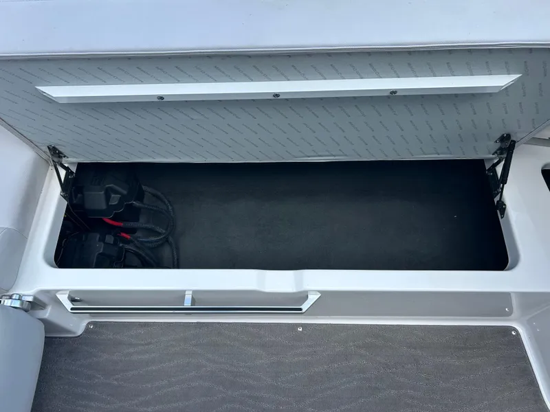 Slide: The Image of 2018 MasterCraft XT23 storage compartment with open lid, showing interior space and wiring. - 9