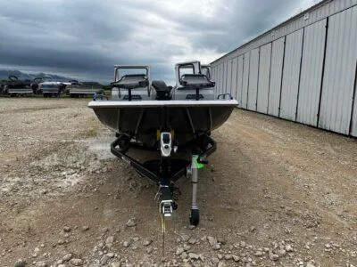 Slide: The Image of 2025 SeaArk ProCat 240 boat on trailer, parked on gravel near storage facility. - 2