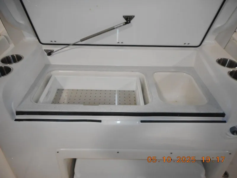 Slide: The Image of Sea Fox 328 Commander 2025 boat storage compartment with cup holders and open lid. - 17