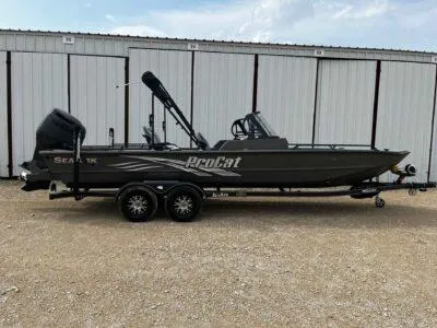 Slide: The Image of 2025 SeaArk ProCat 240 boat on trailer, parked in front of storage units. - 0