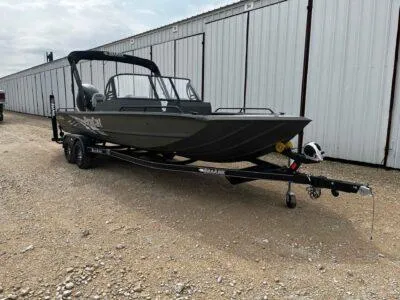 Slide: The Image of 2025 SeaArk ProCat 240 boat on trailer, parked near storage facility. - 1