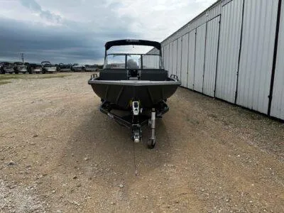 Slide: The Image of 2025 SeaArk ProCat 240 boat on trailer, parked near storage facility. - 2