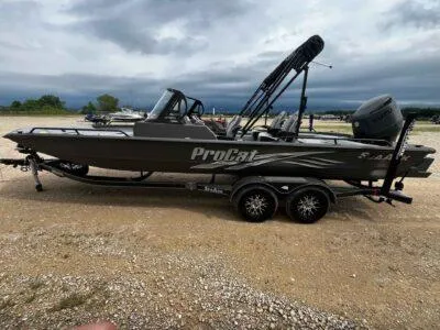 Slide: The Image of 2025 SeaArk ProCat 240 boat on trailer, parked outdoors under cloudy sky. - 4