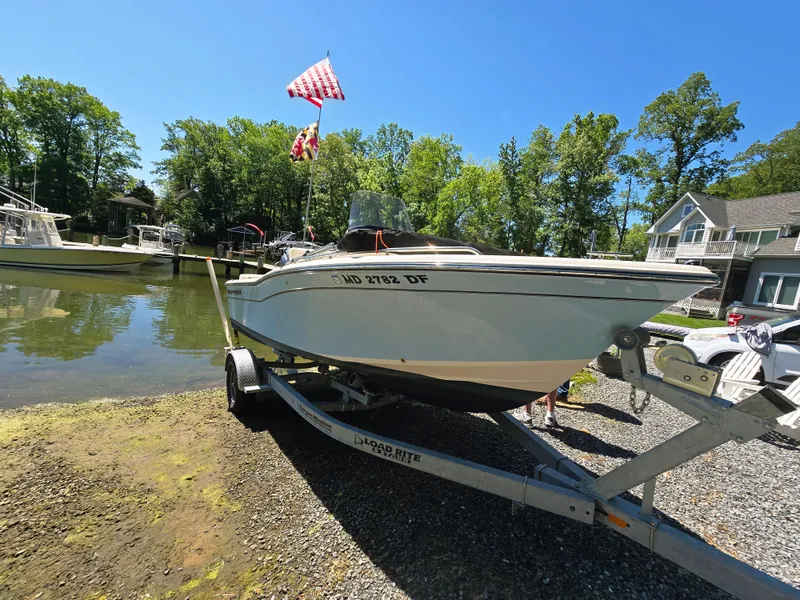 Slide: The Image of 2023 Grady-White Fisherman 180 boat on trailer by a lakeside, surrounded by trees and houses. - 4
