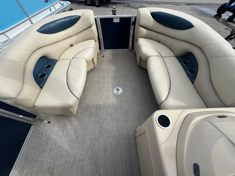 Slide: The Image of 2017 Sylvan Mirage 818 Cruiser interior with beige seating and cup holders. - 9