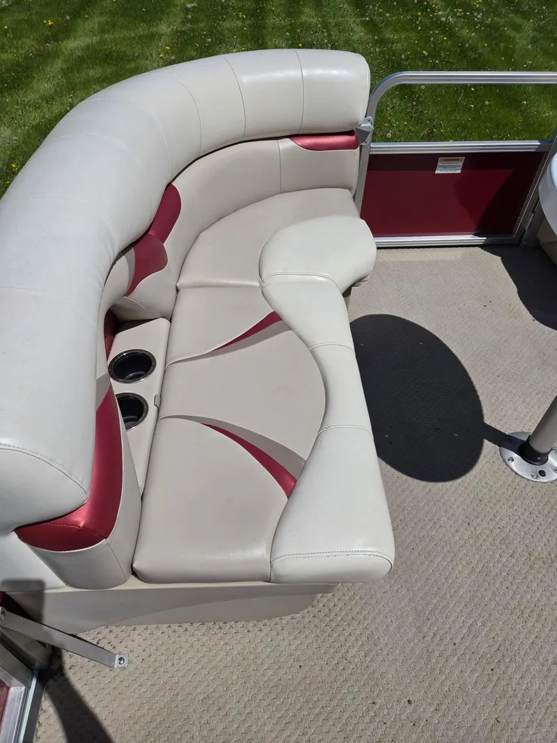 Slide: The Image of 2011 Sylvan Mirage 8520 boat interior with beige and red seating, cup holders, and carpeted floor. - 11