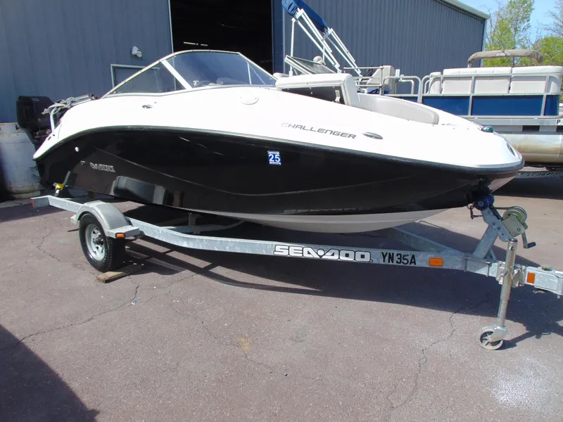 Slide: The Image of 2011 Sea-Doo 180 Challenger SE boat on trailer, parked outdoors near a building. - 1