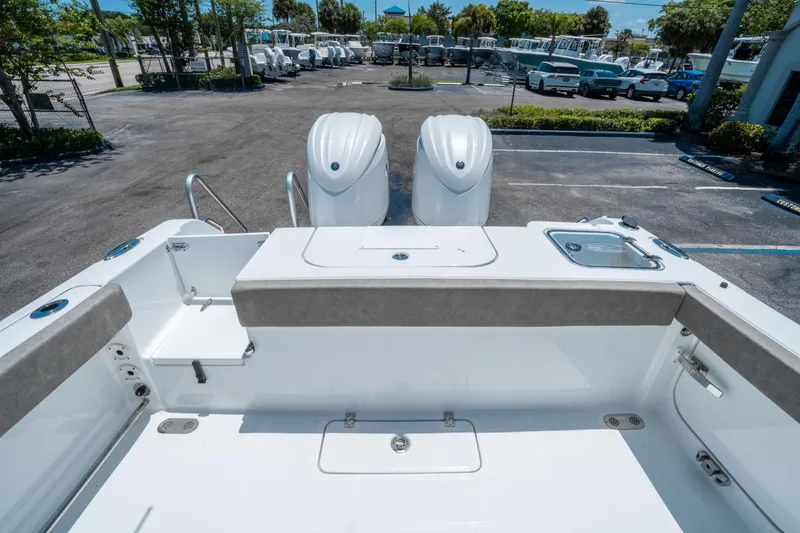 Slide: The Image of 2025 Sea Hunt Gamefish 25 boat deck with dual engines in a parking lot. - 10