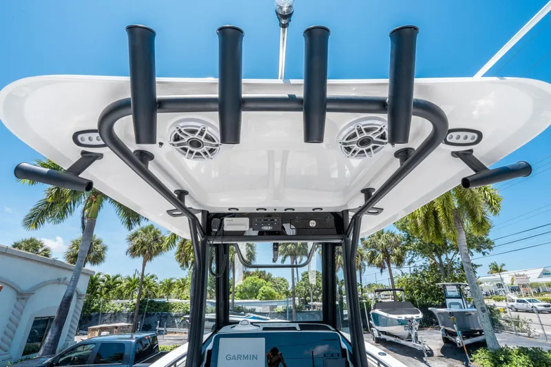 Slide: The Image of 2025 Sea Hunt Gamefish 25 boat with T-top rod holders and speakers, under clear blue sky. - 16
