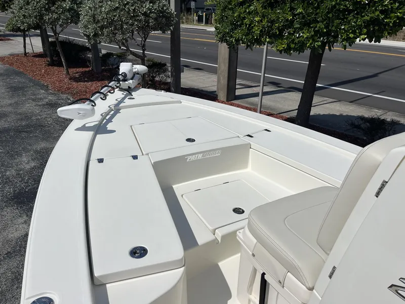 Slide: The Image of 2025 Pathfinder 2300 HPS boat, white deck, seating, and storage compartments, parked near a road. - 13