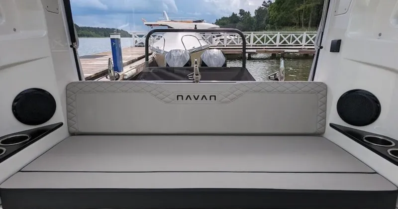 Slide: The Image of 2025 Navan C30 boat interior with cushioned seating, docked by a scenic lake. - 32