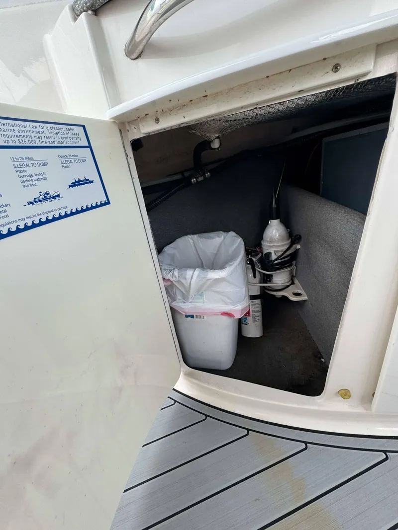Slide: The Image of Storage compartment on a 2007 Chaparral SSX 276 boat, containing a trash bin and equipment. - 26