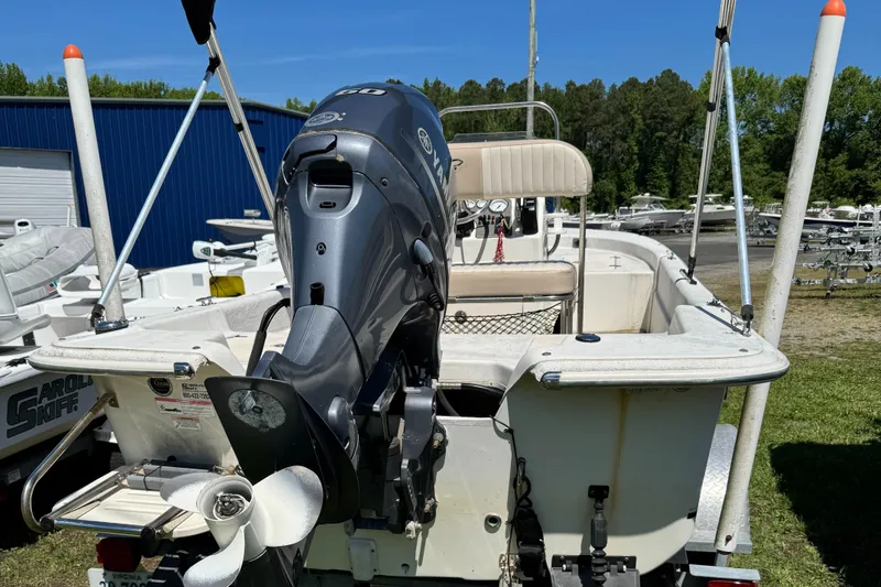 Slide: The Image of 2016 Carolina Skiff J16 boat with outboard motor, parked outdoors near blue building. - 4