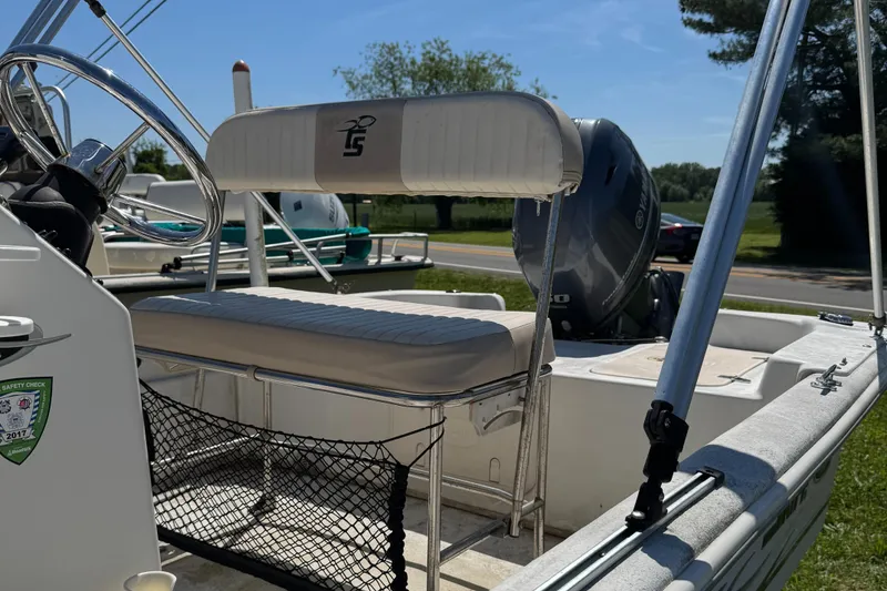 Slide: The Image of 2016 Carolina Skiff J16 boat interior with seating and motor, parked outdoors. - 6