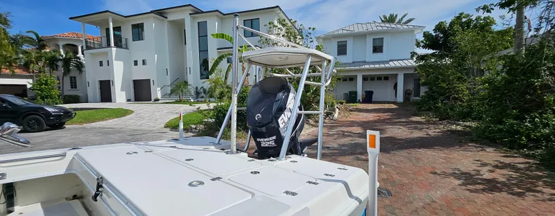 Slide: The Image of 2007 Young Boats 20 Bay in front of modern white house with lush greenery. - 5