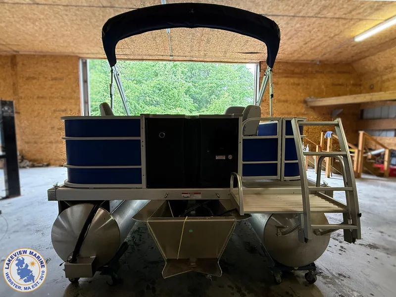 Slide: The Image of 2024 Bennington 20 SXSNP pontoon boat in a garage, featuring blue panels and a canopy. - 11