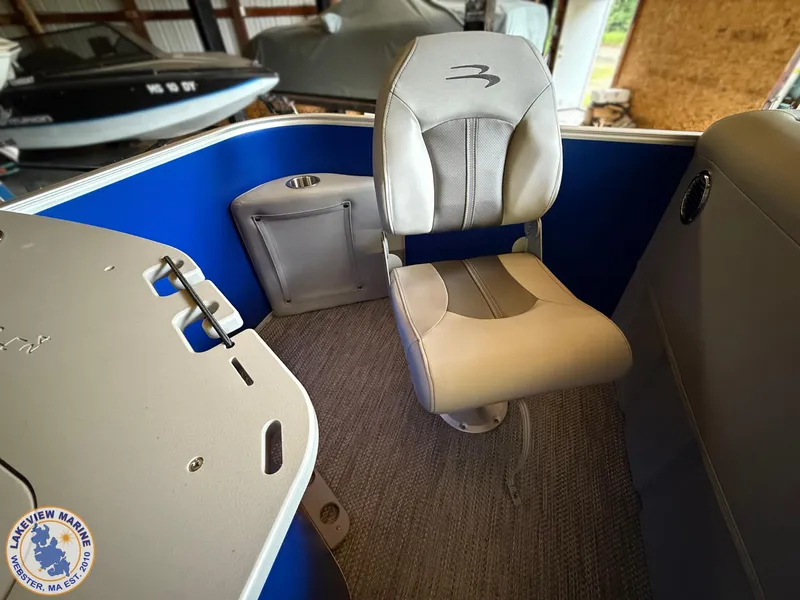 Slide: The Image of 2024 Bennington 20 SXSNP boat interior with gray seating and blue accents in a showroom. - 8