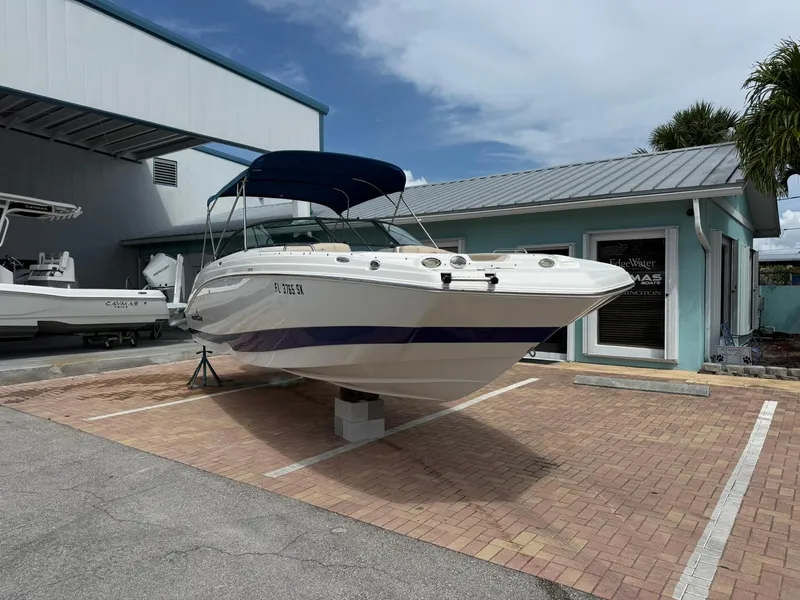 Slide: The Image of 2018 NauticStar 243DC Sport Deck boat parked outside a building under a blue sky. - 2