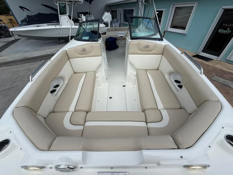 Slide: The Image of 2018 NauticStar 243DC Sport Deck boat with beige seating and open deck layout. - 27