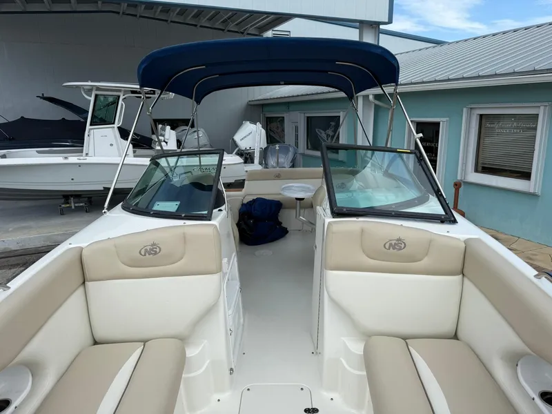 Slide: The Image of 2018 NauticStar 243DC Sport Deck boat with beige seating and blue canopy. - 28