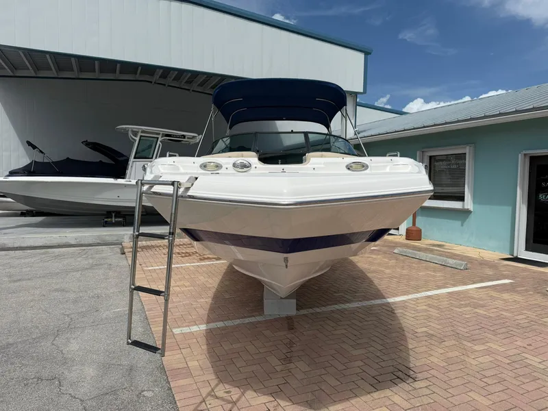 Slide: The Image of 2018 NauticStar 243DC Sport Deck boat with blue canopy, parked on brick pavement. - 4