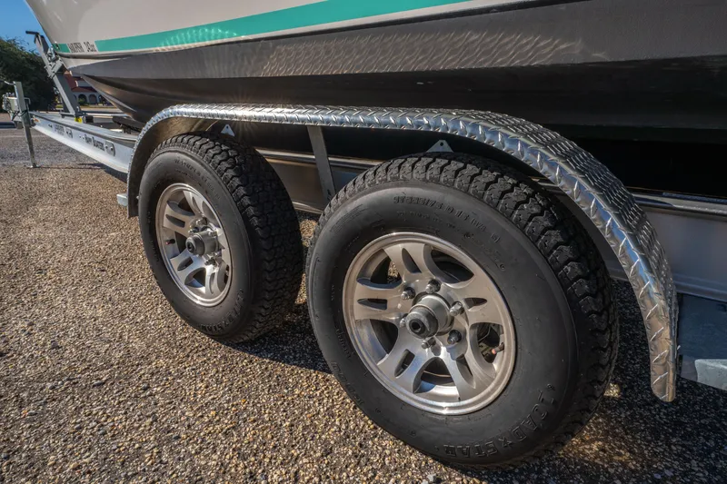 Slide: The Image of Trailer wheels of a 2022 Sailfish 242CC boat on a gravel surface. - 35