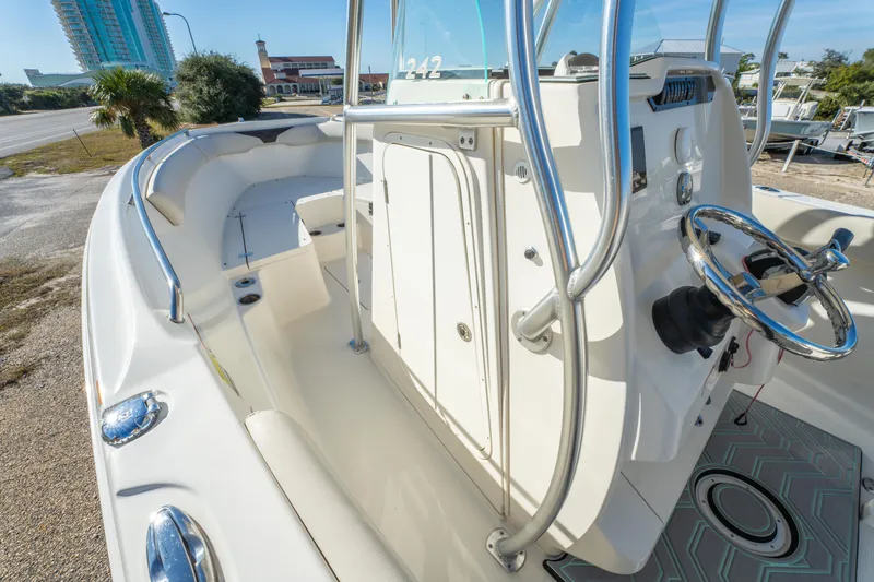 Slide: The Image of 2022 Sailfish 242CC boat interior with steering wheel and seating, docked near a coastal road. - 42