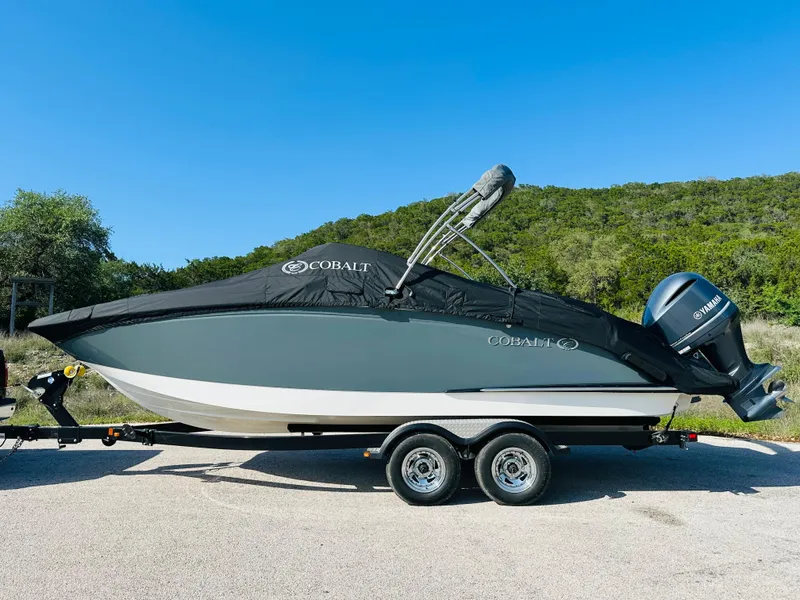 Slide: The Image of 2018 Cobalt 23SC boat on trailer, covered, with scenic background. - 11