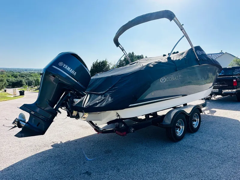 Slide: The Image of 2018 Cobalt 23SC boat with Yamaha outboard motor on a trailer, covered and parked outdoors. - 14
