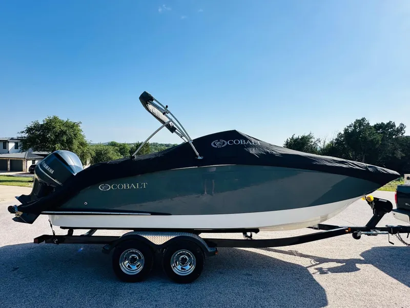 Slide: The Image of 2018 Cobalt 23SC boat on trailer with cover, parked outdoors under clear blue sky. - 15