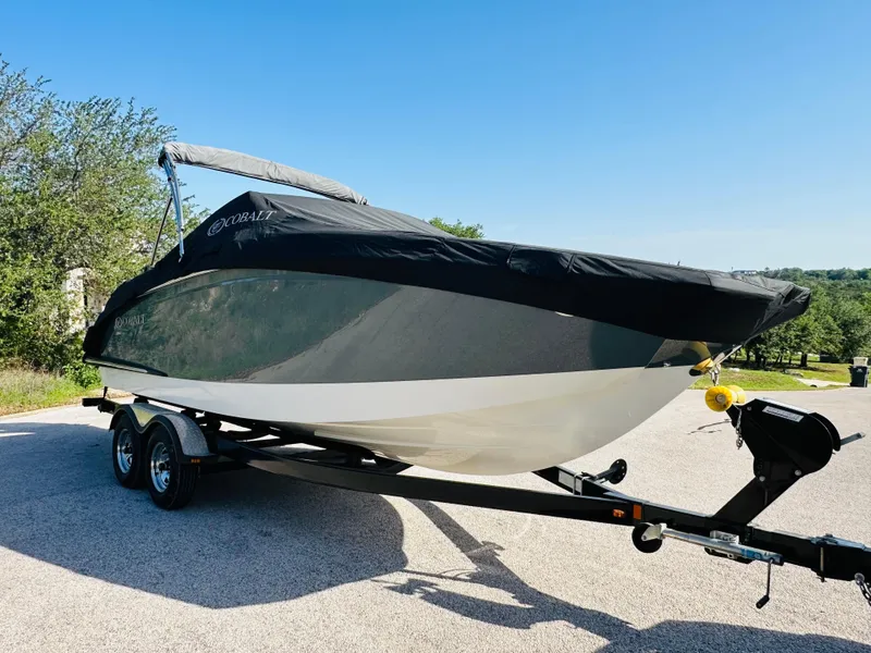 Slide: The Image of 2018 Cobalt 23SC boat on trailer, covered, parked outdoors on sunny day. - 16