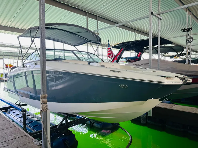 Slide: The Image of 2018 Cobalt 23SC boat docked in a covered marina with an American flag. - 18